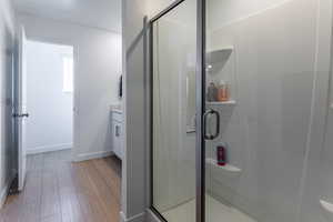 Full bath with vanity, light wood-style flooring, and a shower stall