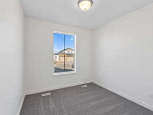 Empty room with baseboards and dark carpet