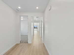 Corridor featuring light wood-type flooring and recessed lighting