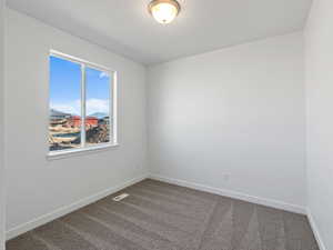 Carpeted spare room featuring baseboards