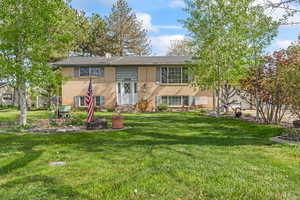 Split foyer home featuring a front lawn, brick siding, a garage, and entry steps
