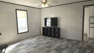 Living room featuring wood-style vinyl flooring, ornamental molding, and ceiling fan