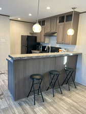 Kitchen featuring a kitchen breakfast bar, light wood-type flooring, a peninsula, wallpapered walls, and light countertops