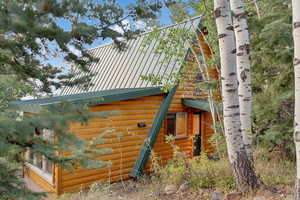 View of side of home featuring a metal roof and log veneer siding