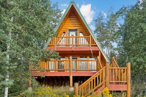 Back of house with a wooden deck, stairway, and log exterior
