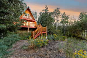 Back of property at dusk featuring a wooden deck and stairway