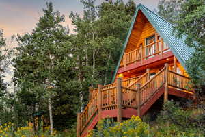 Property exterior at dusk with a metal roof, a view of trees, and stairs