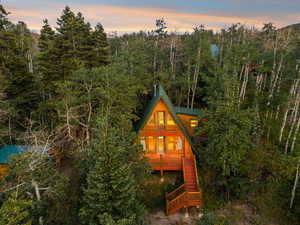 Back of property at dusk with stairway, a view of trees, and covered porch