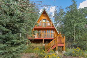 Back of property with a wooden deck, stairway, and a balcony