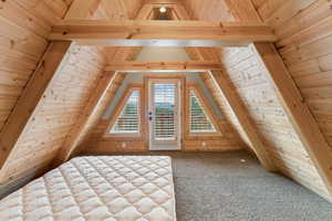 Additional living space with carpet flooring, wood ceiling, and wood walls