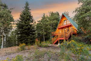 Back of property at dusk with a deck and stairway