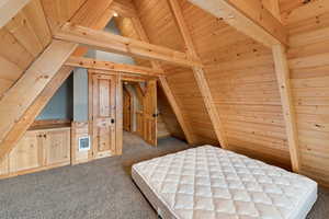 Unfurnished bedroom with wood ceiling, carpet floors, and wooden walls