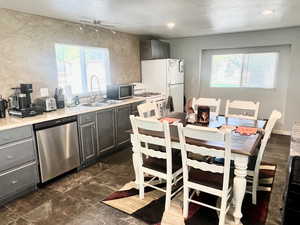 Kitchen with appliances with stainless steel finishes, plenty of natural light, and gray cabinets