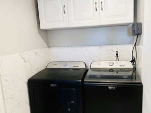 Laundry area featuring washer and clothes dryer and cabinet space