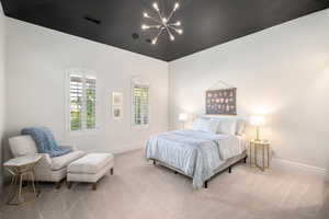 Carpeted bedroom featuring baseboards and a chandelier