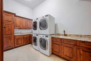 Laundry room featuring cabinet space, light tile patterned floors, and stacked washer / dryer