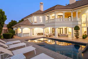 Back of house with a chimney, a patio area, stucco siding, an outdoor hangout area, and a pool with connected hot tub