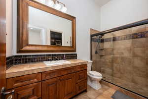 Bathroom featuring backsplash, a stall shower, vanity, and light tile patterned flooring