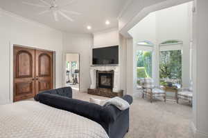 Bedroom with ornamental molding, carpet flooring, a premium fireplace, a high ceiling, and a ceiling fan