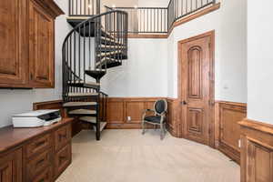 Living area with light carpet, a high ceiling, and wainscoting