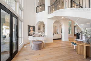 Entryway with light wood-style floors, a towering ceiling, recessed lighting, arched walkways, and french doors