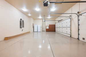 Garage with a garage door opener, freestanding refrigerator, and washer / dryer