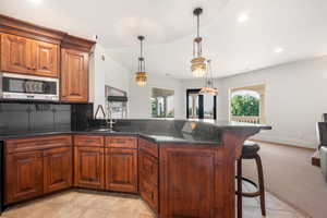 Kitchen featuring brown cabinets, recessed lighting, tasteful backsplash, a breakfast bar area, and a peninsula