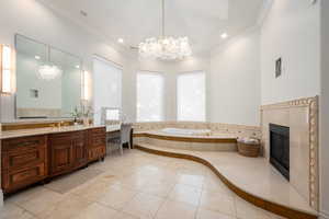 Full bath with a chandelier, a bath, vanity, crown molding, and a high end fireplace