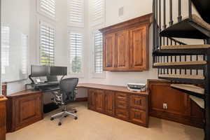 Office space with light colored carpet and a towering ceiling