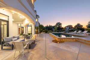 Pool at dusk with a water slide, a patio, an outdoor hangout area, an outdoor pool, and an in-ground hot tub