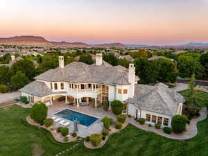 Back of house at dusk with a patio, stucco siding, a chimney, and a mountain view
