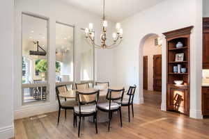 Dining area featuring arched walkways, light wood finished floors, and a chandelier