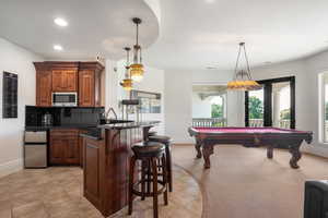 Kitchen featuring a peninsula, tasteful backsplash, a kitchen breakfast bar, appliances with stainless steel finishes, and decorative light fixtures
