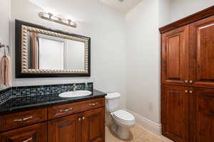 Half bathroom with vanity, light tile patterned floors, and decorative backsplash