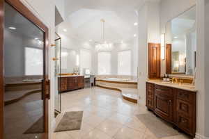 Full bathroom with two vanities, crown molding, a bath, light tile patterned floors, and a chandelier