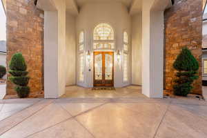 Property entrance featuring french doors, stone siding, and stucco siding