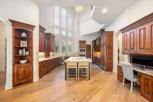Kitchen with arched walkways, a kitchen bar, a kitchen island, glass insert cabinets, and a high ceiling