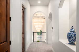 Hallway featuring light carpet and a chandelier