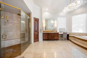 Full bath featuring vanity, crown molding, a shower stall, a garden tub, and light tile patterned floors