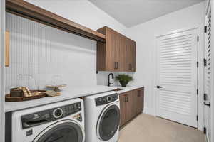 Laundry room with light tile patterned floors, washing machine and clothes dryer, and cabinet space