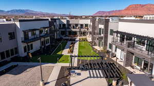 View of community with an area to practice putting, a mountain view, a pergola, and a balcony