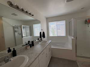 Bathroom with a shower stall, a garden tub, double vanity, dark tile patterned flooring, and a textured ceiling