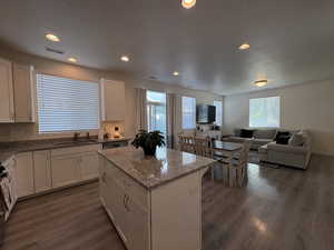 Kitchen featuring white cabinetry, recessed lighting, a center island, light stone counters, and open floor plan