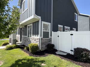 View of property exterior with a gate, board and batten siding, and stone siding