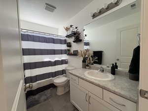 Full bath featuring a textured ceiling, vanity, and dark tile patterned floors