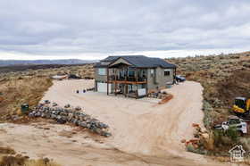 Back of house featuring a mountain view, a balcony, and a desert view