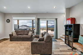 Living room with wood finished floors, healthy amount of natural light, stairs, and recessed lighting