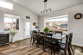 Dining area with vaulted ceiling, dark wood finished floors, and track lighting