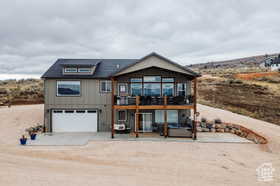 View of front of property featuring concrete driveway, an attached garage, a patio, and a wooden deck