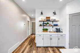 Bar area with recessed lighting, light countertops, dark wood finished floors, white cabinets, and open shelves
